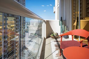 A balcony with a view of a cityscape, a cactus plant, and a red chair. - Designer Remodeled Strip View Suite With Balcony at the MGM Signature Las Vegas (Las Vegas)
