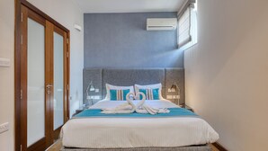 Une chambre d’hôtel avec un lit, une porte en bois, un climatiseur fixé au mur et une fenêtre.
