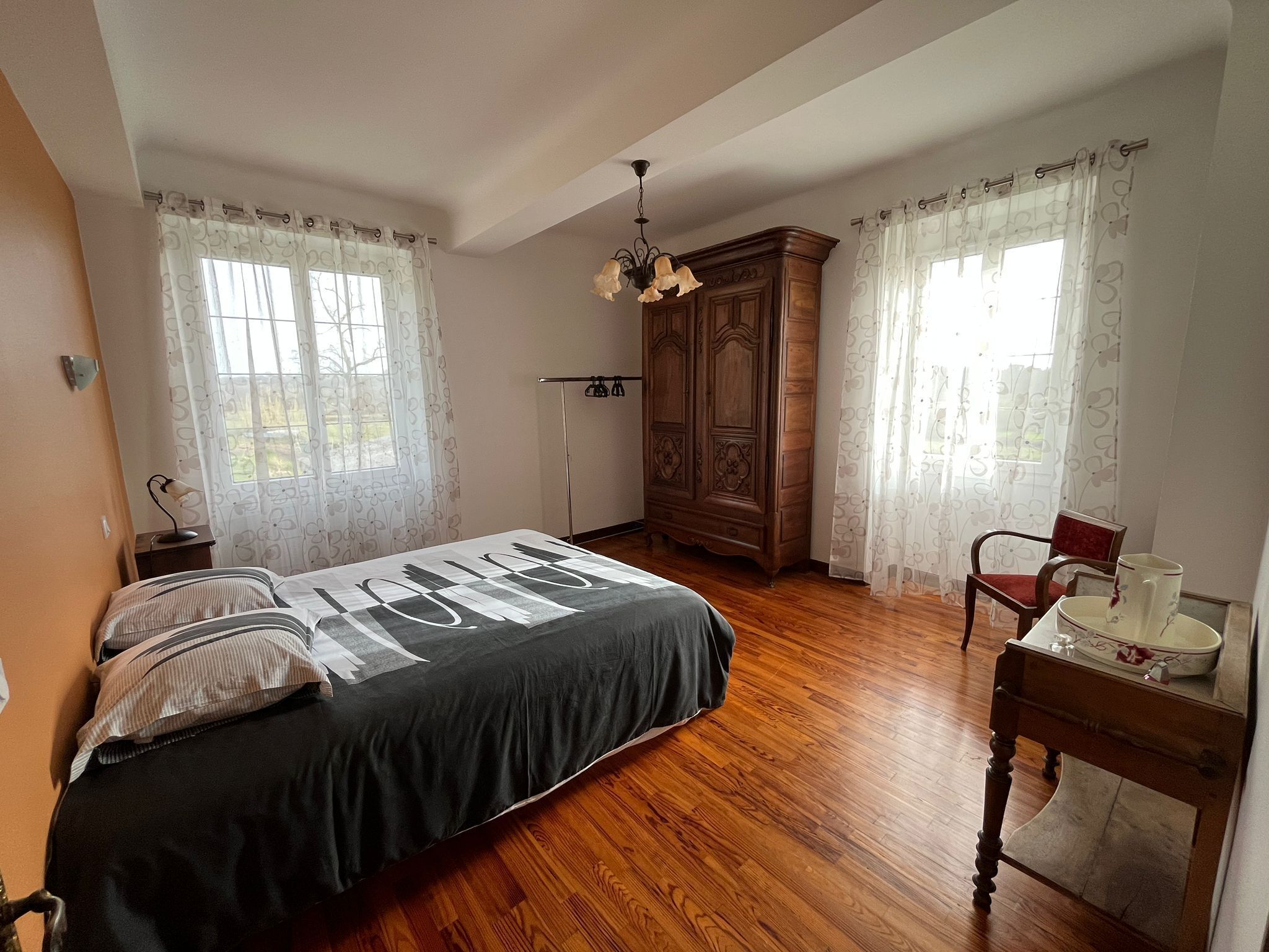 A bedroom with a bed, wooden wardrobe, and a desk with a chair.