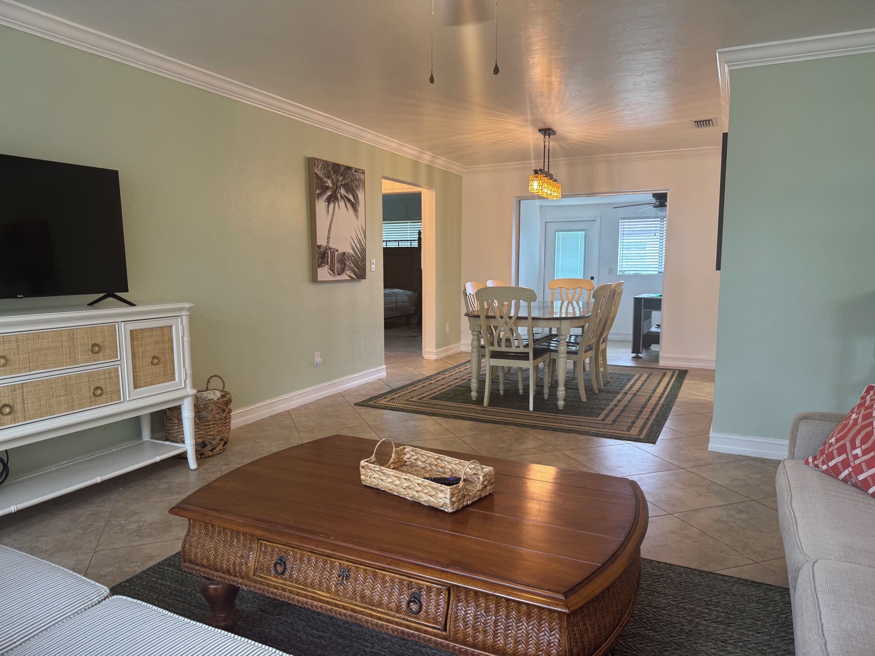 A living room with a television, a wooden coffee table, a dining table with chairs, and a sofa.