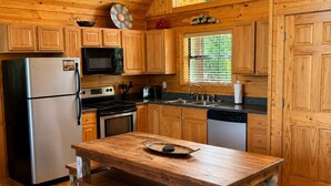 Eine Küchenzeile im Holzblockhaus-Stil mit Kühlschrank, Herd, Mikrowelle, Spüle und Holzausstattung.
