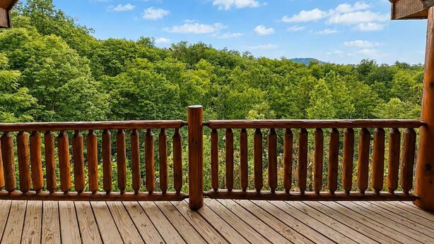 Eine Holzterrasse mit Geländer, mit Blick auf eine bewaldete Landschaft.