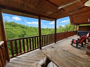 Eine Holzterrasse mit Geländer, Grill und Bank.