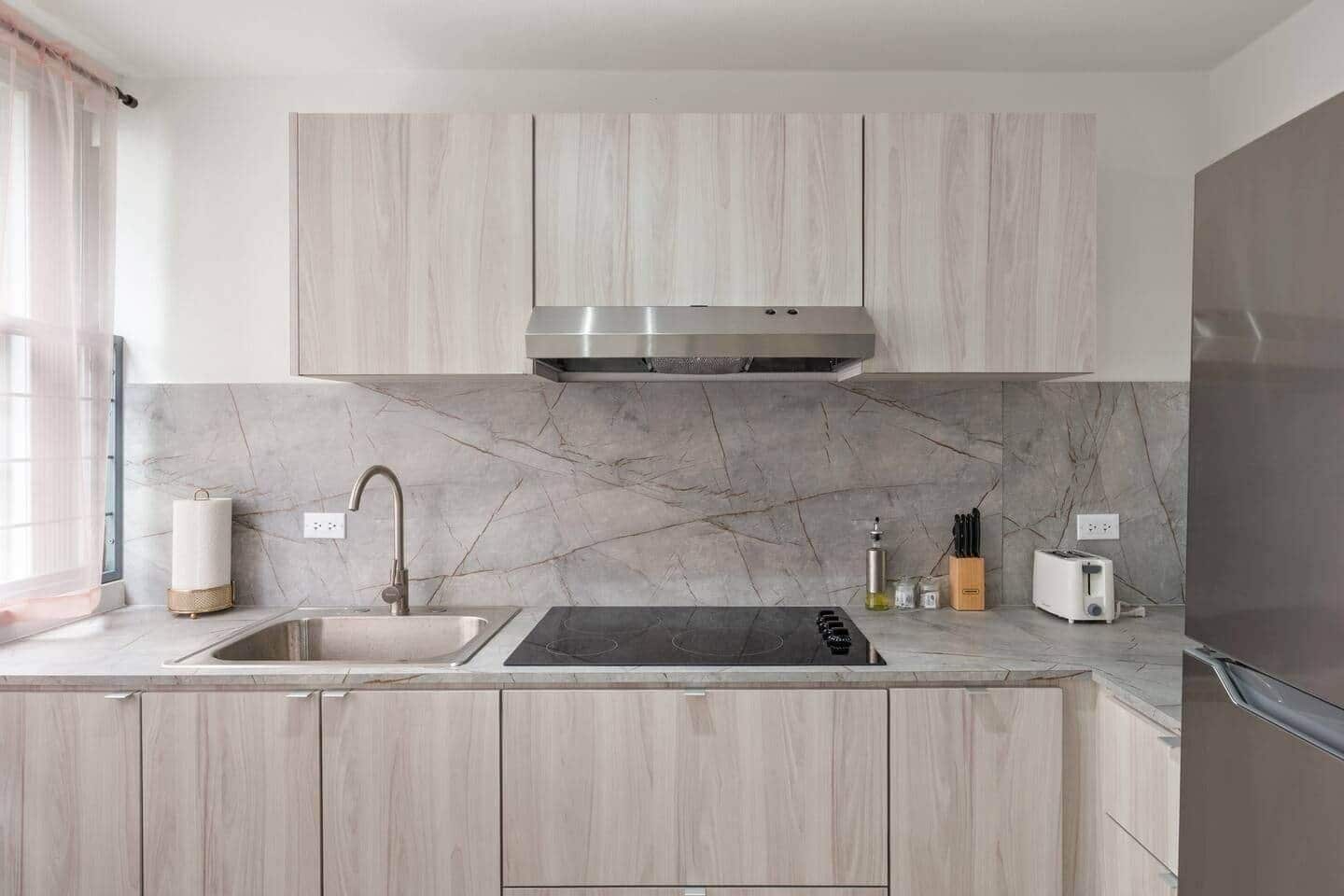 A modern kitchen with a built-in stove, sink, and stainless steel appliances.