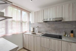A modern kitchen with a marble backsplash, stainless steel appliances, and light wood cabinetry. - Cozy 3BR Condo Pool  10 minutes to Airport (Carolina)