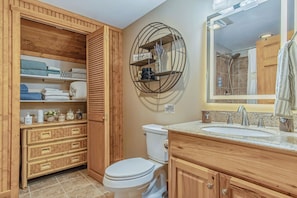 Een badkamer met een houten wastafelmeubel, toilet en douche.