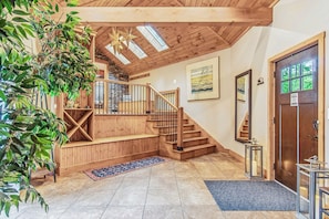 Un escalier en bois avec une rampe, un banc en bois, un tapis bleu et une porte avec une pancarte.