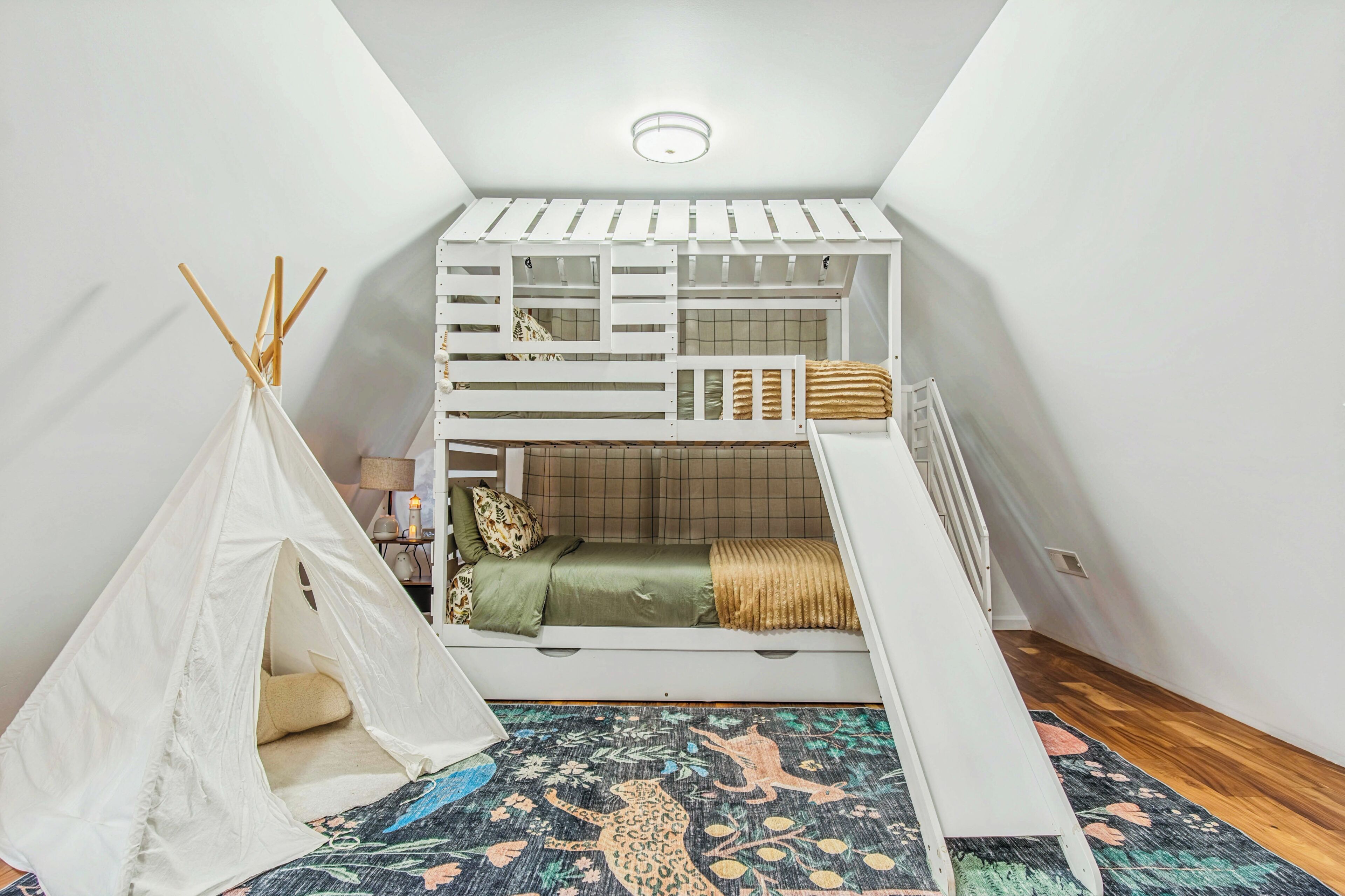 Un dormitorio tipo loft con una cama litera, una tienda de campaña y una alfombra colorida.