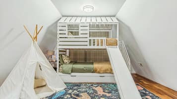Un dormitorio tipo loft con una cama litera, una tienda de campaña y una alfombra colorida.