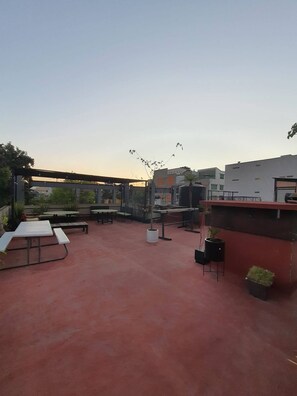 Ein Terrassenbereich im Freien mit Tischen und Stühlen, umgeben von Gebäuden.