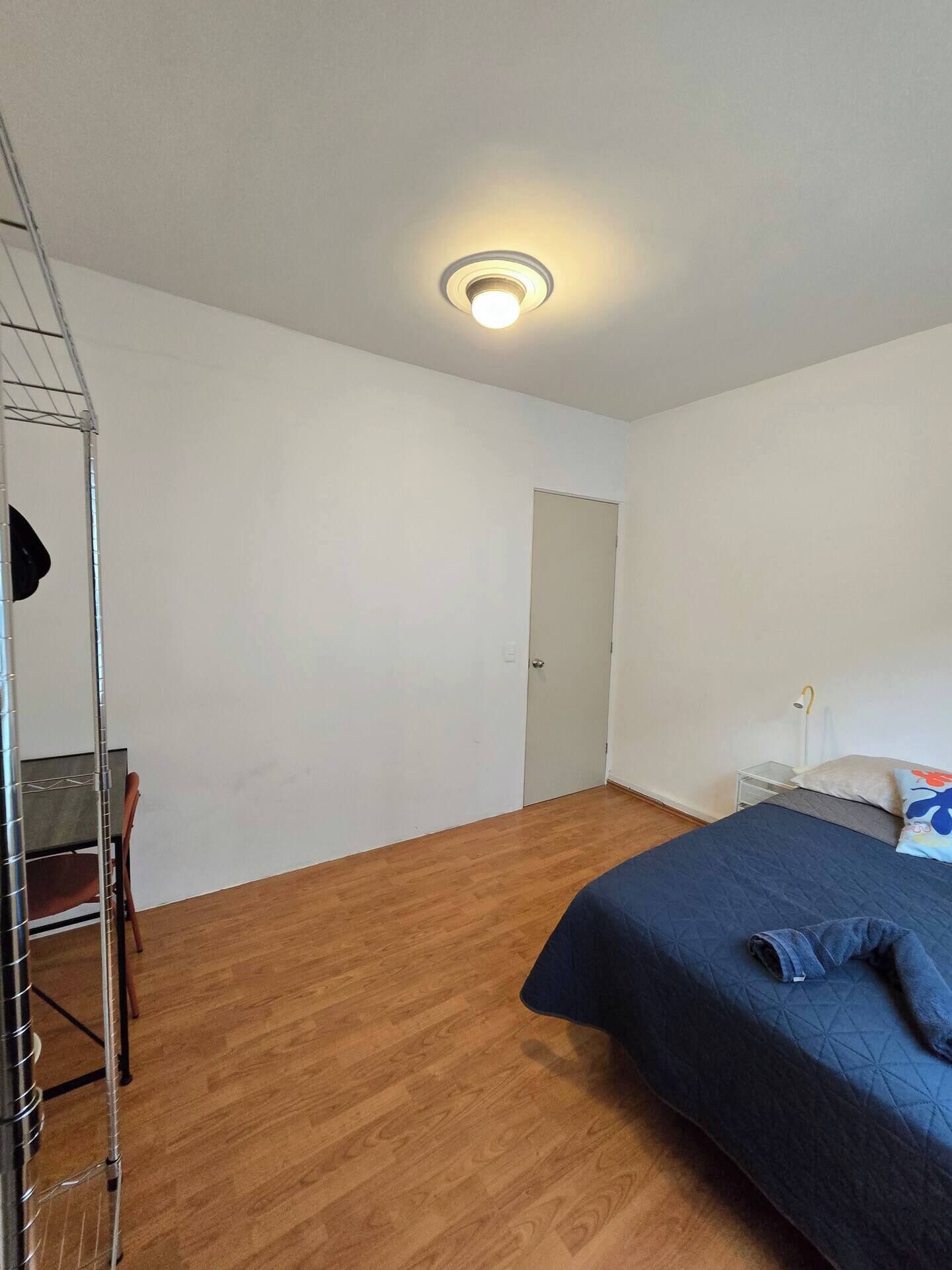 Una habitación con cama, una silla, un armario y una puerta.