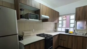 A kitchen with wooden cabinets, a stove, a microwave, and a refrigerator. - Apartment in Condesa with a Terrace (Ciudad de México)