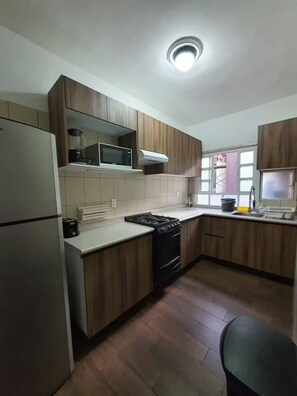 A kitchen with wooden cabinets, a stove, a microwave, and a refrigerator. - Apartment in Condesa with a Terrace (Ciudad de México)