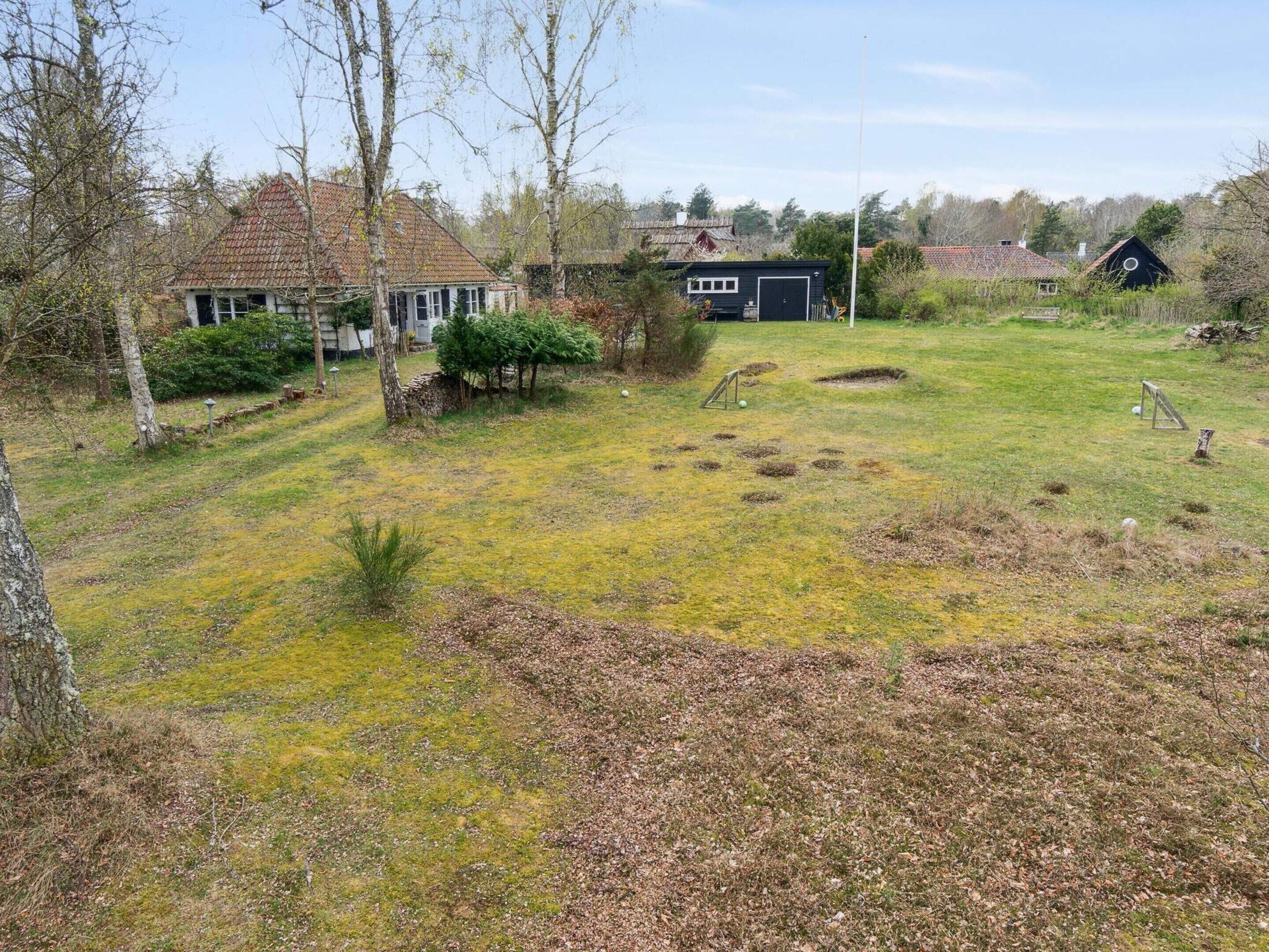 A rural property with a house, a barn, and a grassy yard with scattered trees.