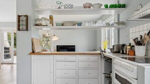 Una cocina con armarios blancos, encimera de madera, horno empotrado y ventana.