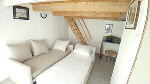 Ein kleines Zimmer mit Schlafsofa, Schreibtisch und Stuhl.