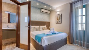 Quarto de hotel com cama, banheiro e uma grande janela com cortinas.