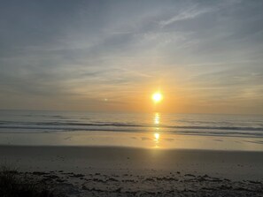 Uma praia com o sol refletindo na água.