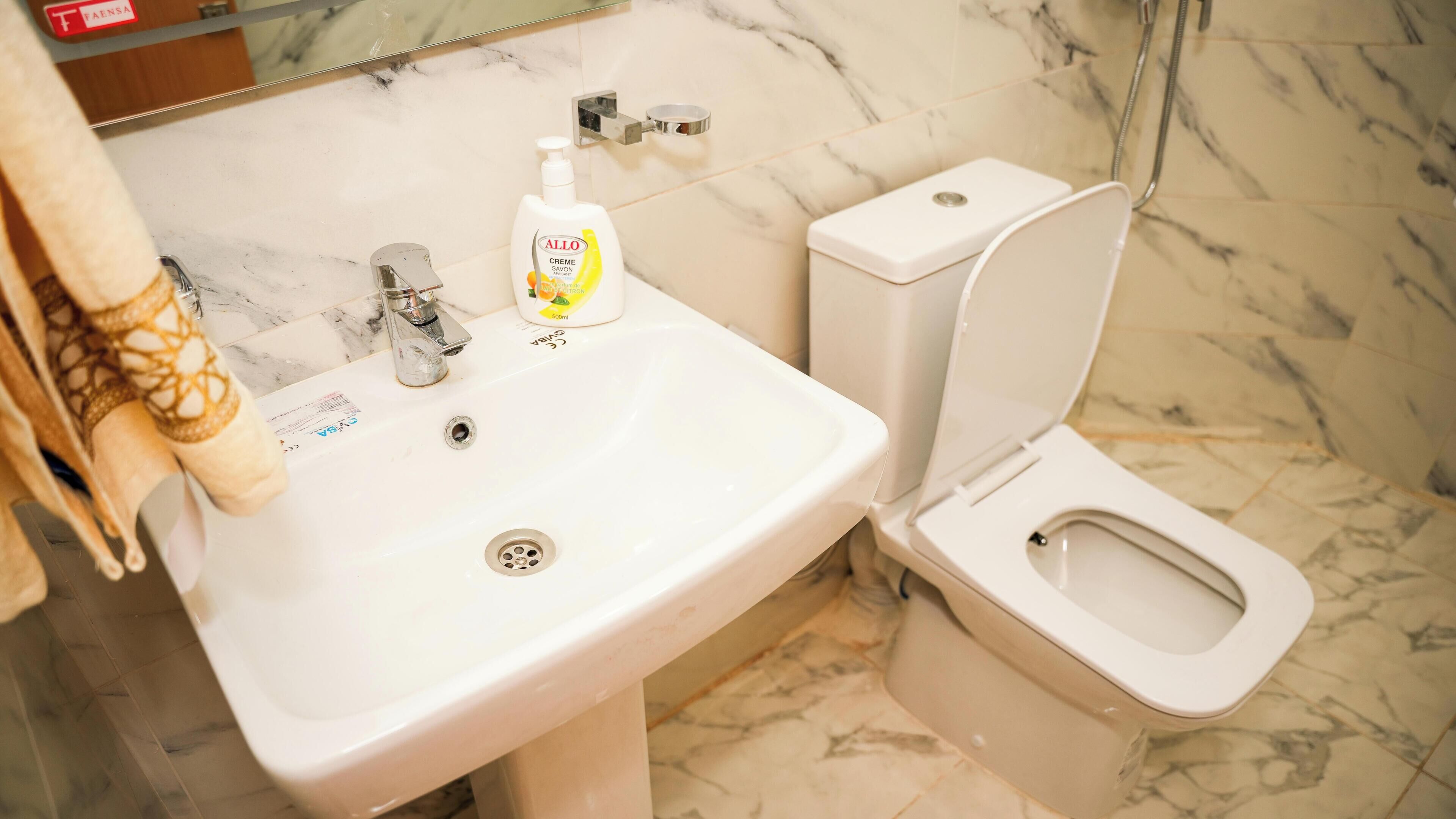 Une salle de bain avec un lavabo blanc, des toilettes et une douche.