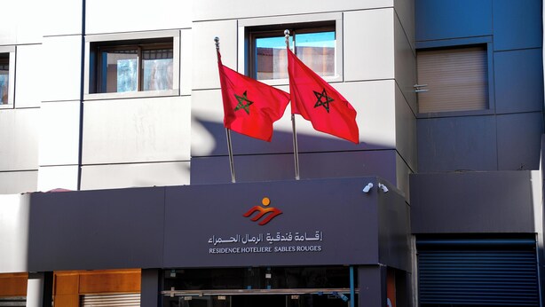 Rakennuksessa on kaksi lippua, logo ja arabiankielinen kyltti.