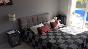 A bedroom with a bed, pillows, a nightstand, a lamp, and a suitcase. - Beautiful 3-bedroom apartment (70 square meters) in Juan (Antibes)