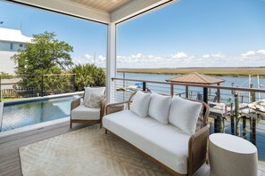 Ein Balkon mit Pool, einer Couch und Blick auf das Wasser.