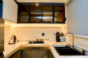 A modern kitchen with a gas stove, a kettle, and a sink.