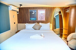 A hotel room with a bed, a nightstand, a wardrobe, and a mirror.