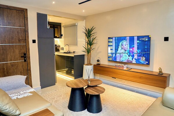 A modern living room with a TV, sofa, coffee table, and a plant.