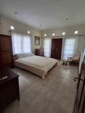 Ein Schlafzimmer mit einem großen Bett, einem Holzschrank, einem Schreibtisch, einem Stuhl und einer Tür.