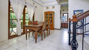 Un espace repas comprenant une table et des chaises en bois, un buffet et un escalier.