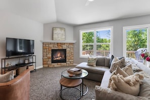 Ein Wohnzimmer mit Kamin, Fernseher, Sofa und Couchtisch.