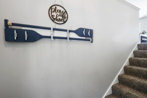 A wall-mounted paddleboard rack with a 'Please remove your shoes' sign above it. - Lakebreeze Hideaway - Lake view of Lake Como in LG (Lake Geneva)