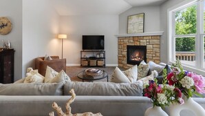 Un salon avec une cheminée en pierre, un téléviseur et un canapé agrémenté de coussins décoratifs.