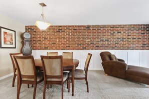 A dining area with a brick wall, a clock, and a hanging light fixture. - Poolside condo by Lake - walk up to Ridge Resort (Lake Geneva)