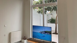 Una sala de estar moderna con un televisor grande, una mesa de centro de cristal y un diseño minimalista.