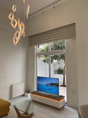 Un salon moderne doté d’un grand téléviseur, d’une table basse en verre et d’un design minimaliste.