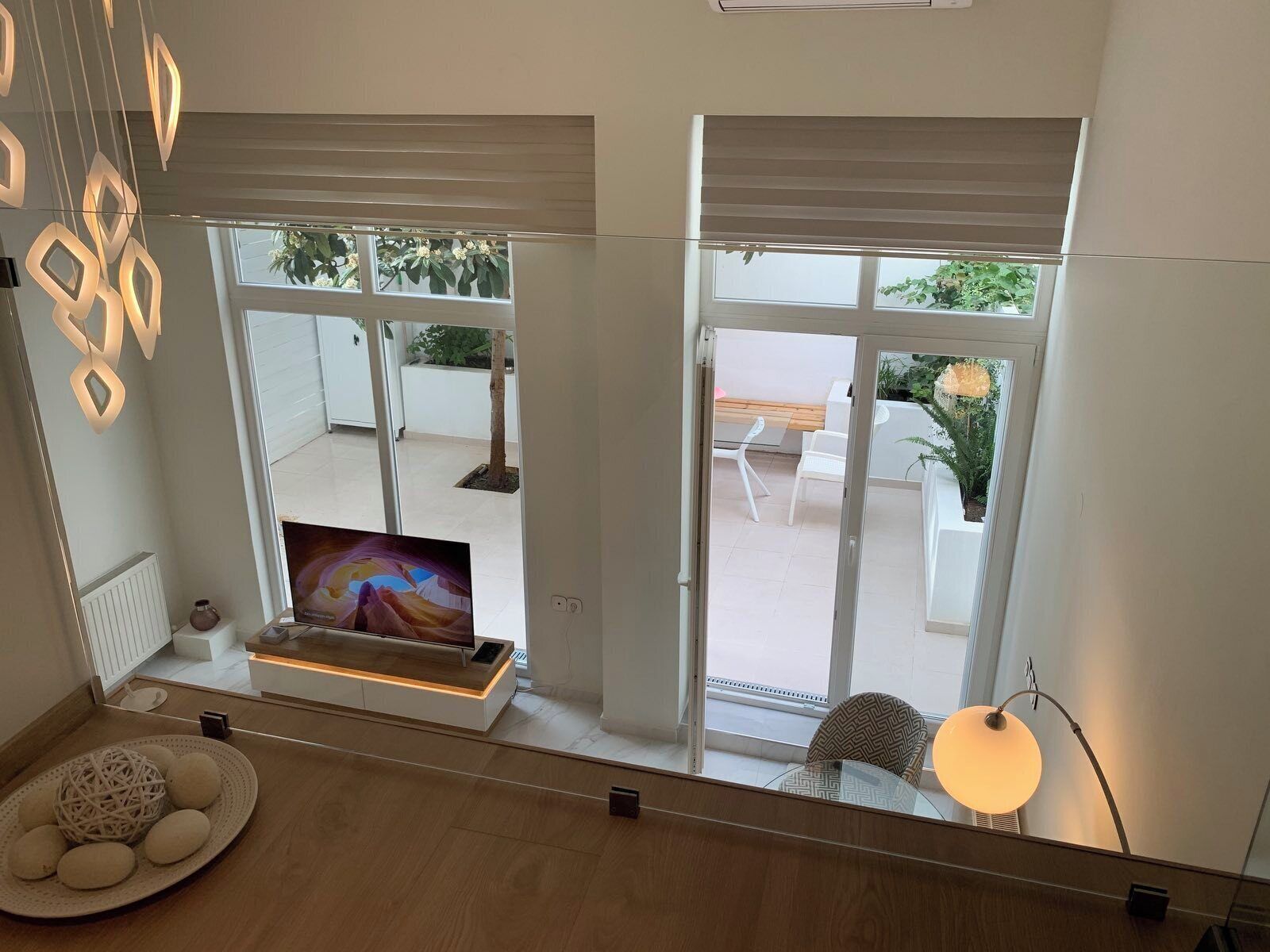 Un soggiorno moderno con una TV, un'area pranzo con sedie e un balcone con piante.
