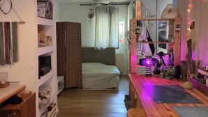 Ein Zimmer mit Bett, Schreibtisch, Regalen und Deckenventilator.