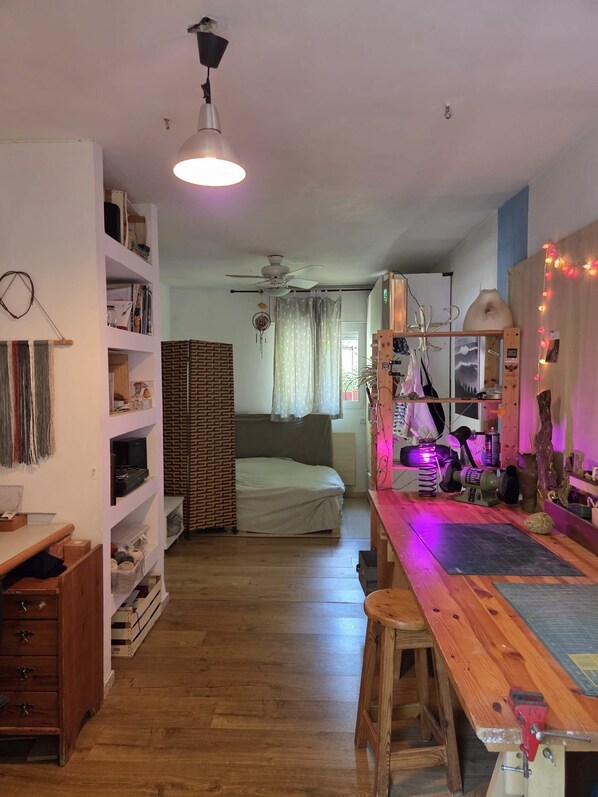 Una habitación con cama, escritorio, estanterías y ventilador de techo.