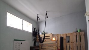 Ein Zimmer mit Yogamatte, einem kleinen Bett, einer Holzwand und einem Fenster.