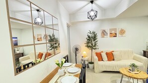 Un salon moderne comprenant un coin repas, un canapé, un ventilateur de plafond et un grand miroir.