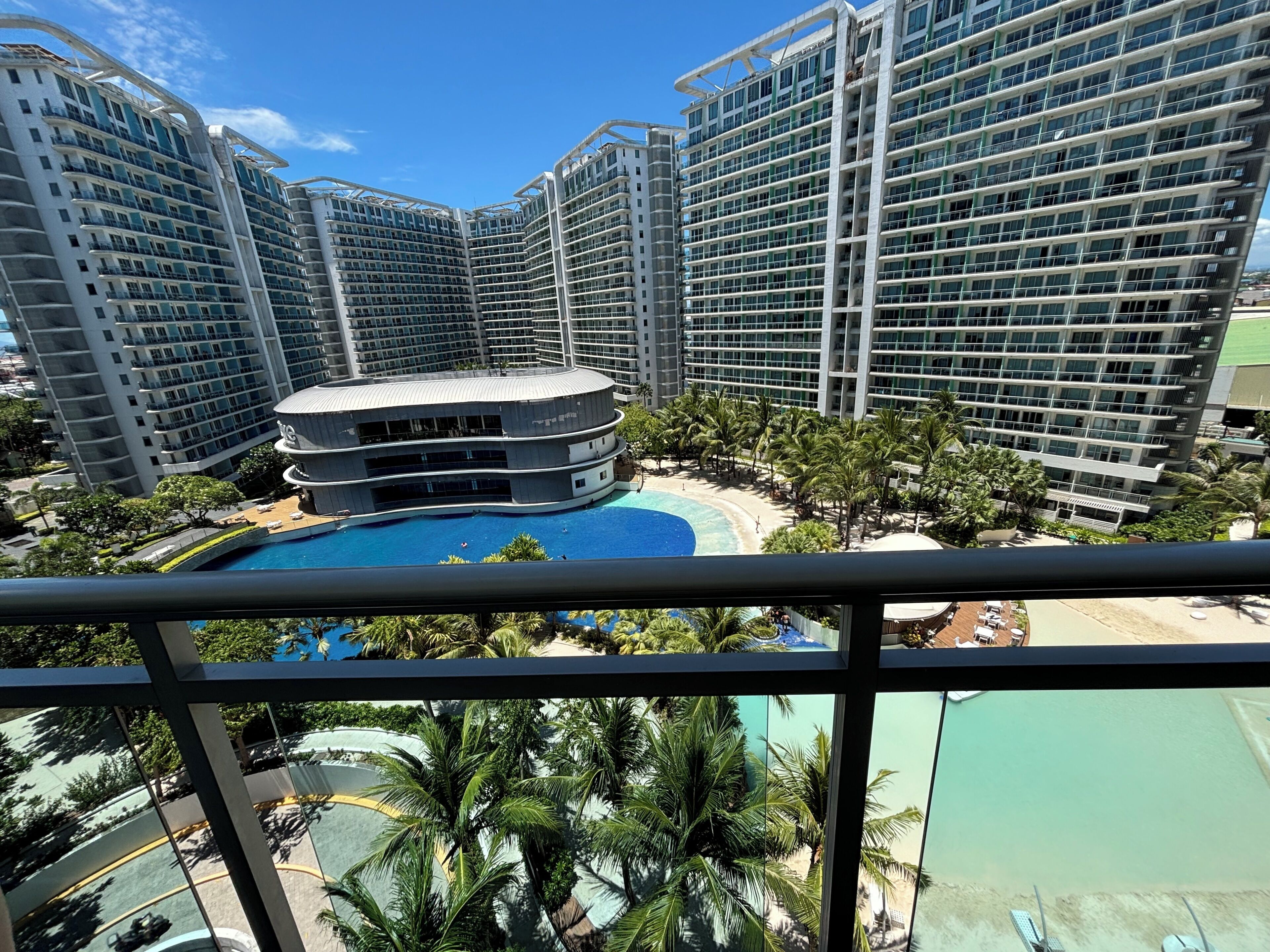 A high-rise hotel with multiple balconies, a central pool, and a beach area.