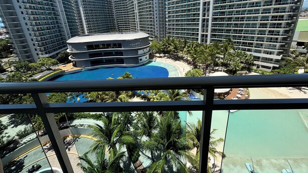 Un hôtel de grande hauteur doté de nombreux balcons, d’une piscine centrale et d’un espace de plage.