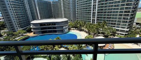 A high-rise hotel with multiple balconies, a central pool, and a beach area.