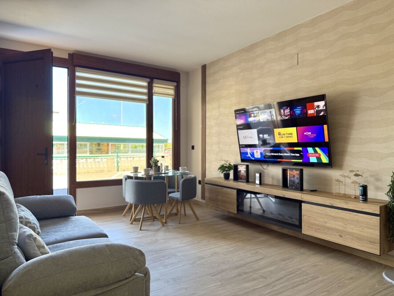 Una sala de estar moderna con televisor de pantalla plana, comedor y balcón con vistas.
