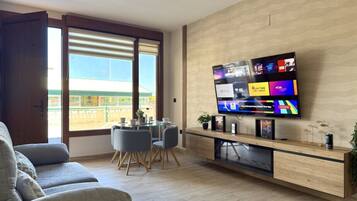 Una sala de estar moderna con televisor de pantalla plana, comedor y balcón con vistas.