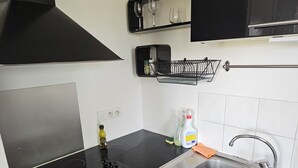 Una cocina compacta con estufa, lavamanos y armarios negros.