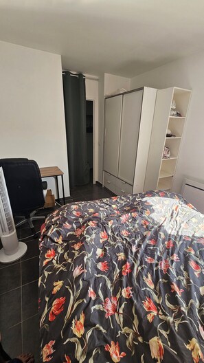 A bedroom with a bed, a desk, a chair, a wardrobe, and a radiator. - Apartment overlooking the Seine 10 minutes from La Défense (Bezons)
