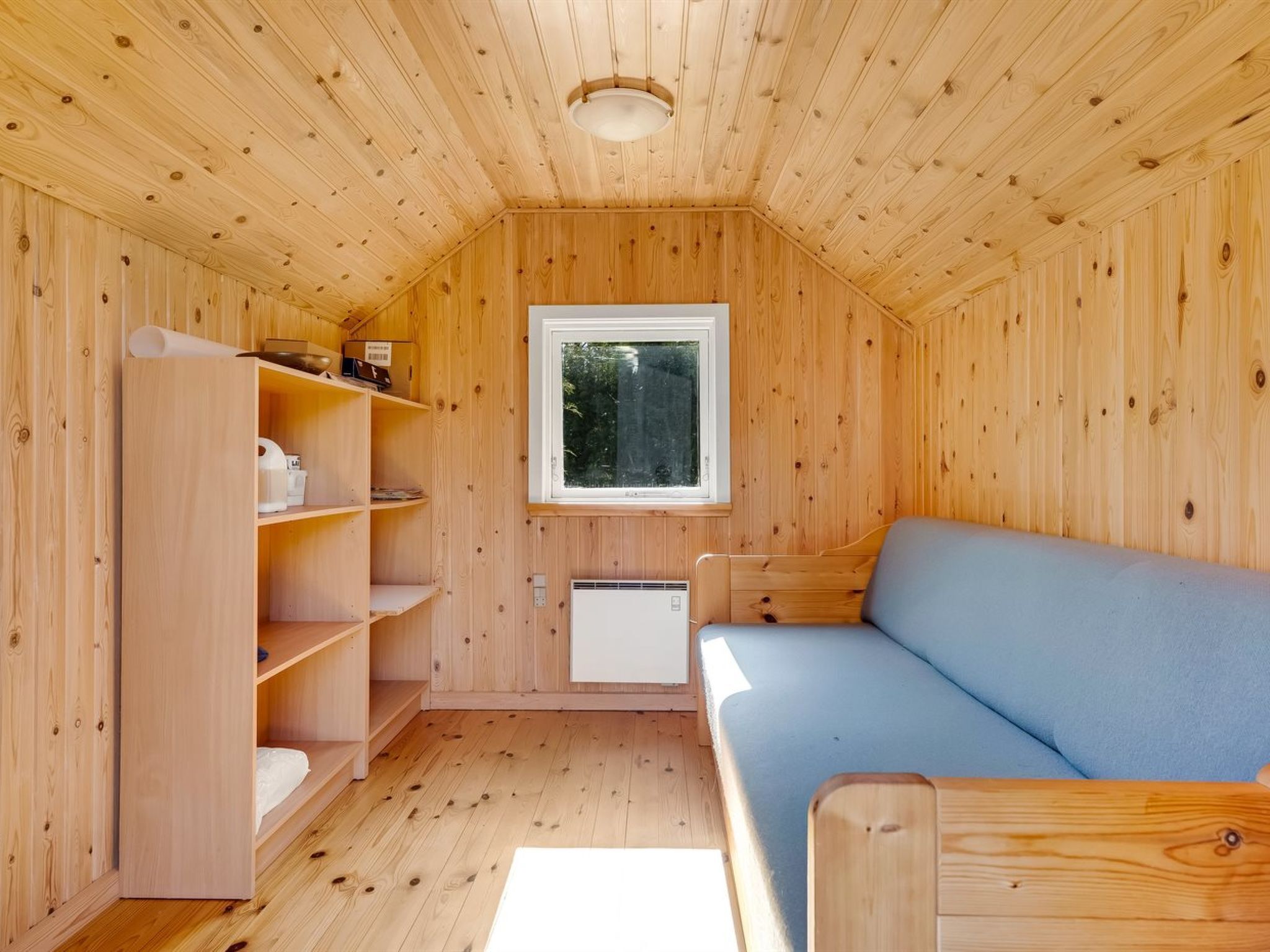 Un intérieur en bois avec un canapé, des étagères et une fenêtre.